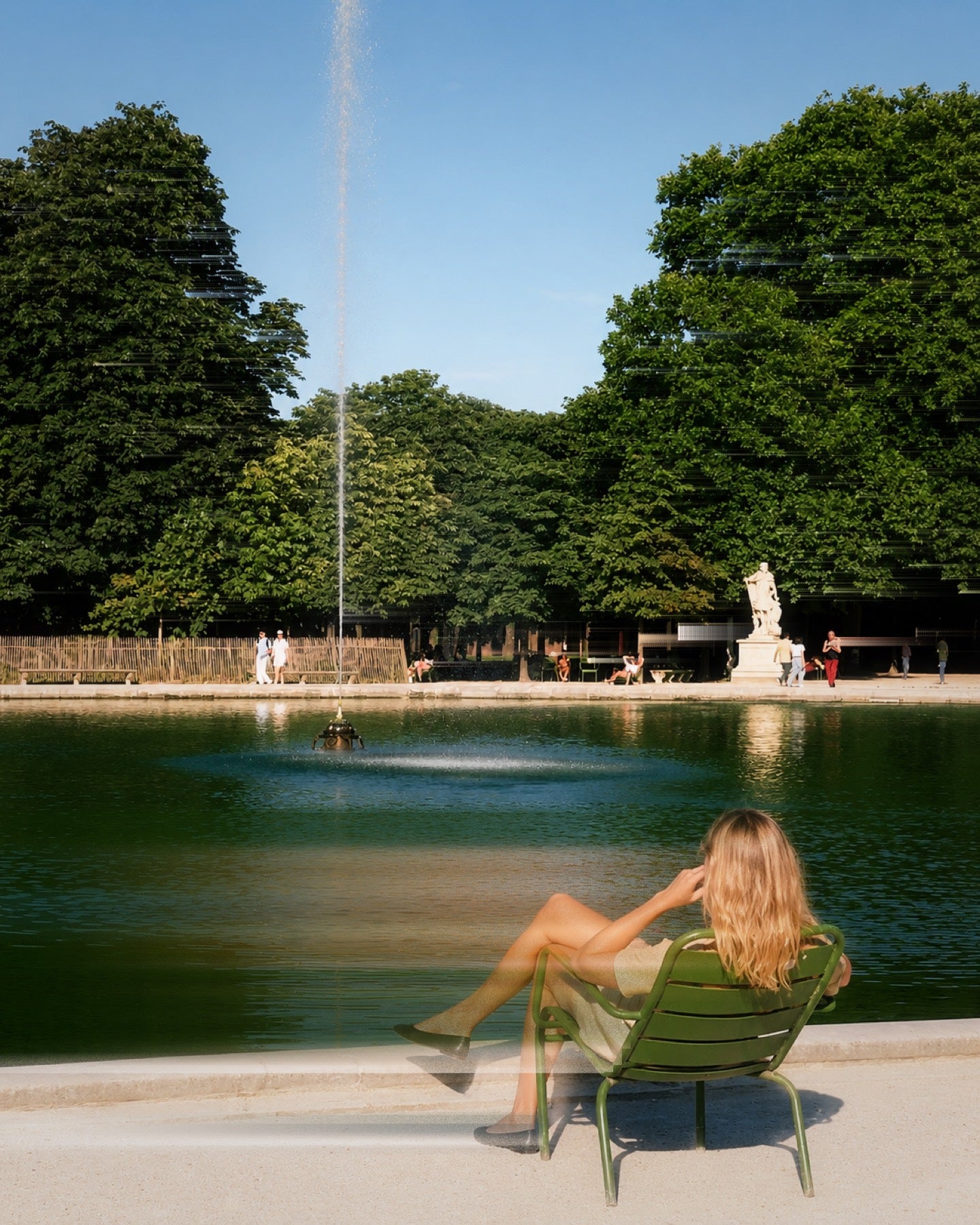 Frau sitzt neben einem Springbrunnen in einem Stadtpark